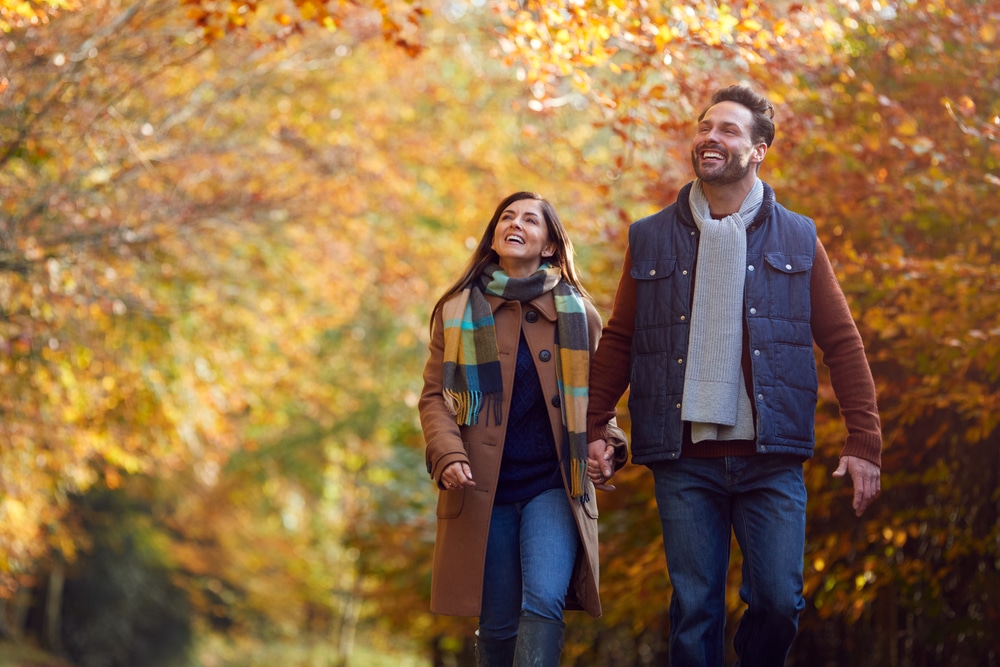 Places to See Fall Foliage in Mid-Michigan this year near Bay City, photo of a couple walking in the woods