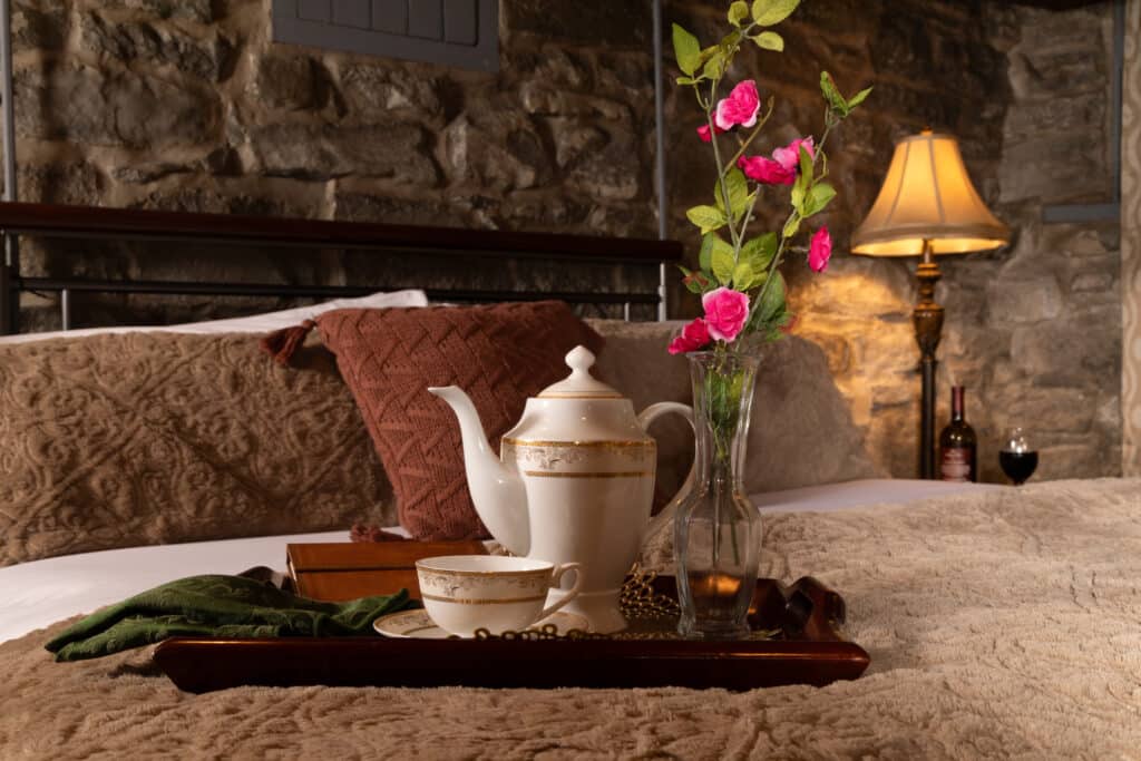 A tray with cup, porcelain coffee pot, and vase of flowers sits on the bed in the Keep Room of the Historic Webster House, the best Bed and Breakfast in Michigan.