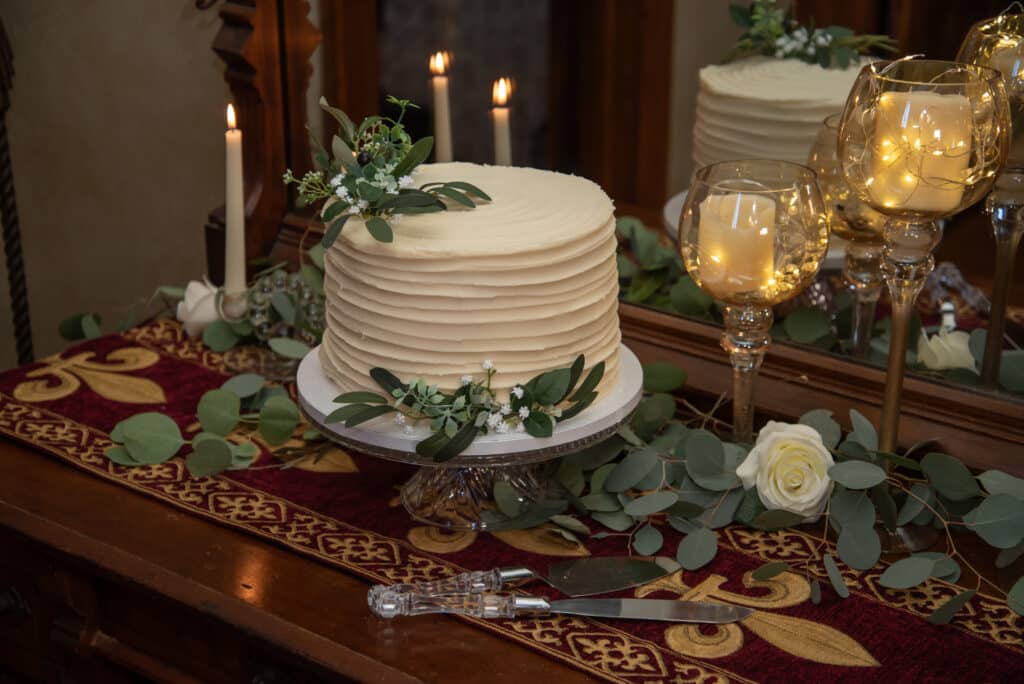 Wedding cake surrounded by candles and greenery at our romantic B&B, one of the best historic Michigan wedding venues.